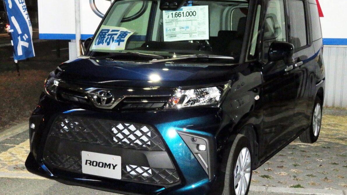 現行ルーミーX（2026年8月改良後）の展示車。フロントガラスに価格ステッカーが貼られた夜間の店頭ショット