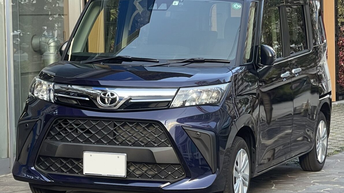 現行ルーミーG 4WD（2026年8月改良後）の外観フロントビュー。建物前で撮影